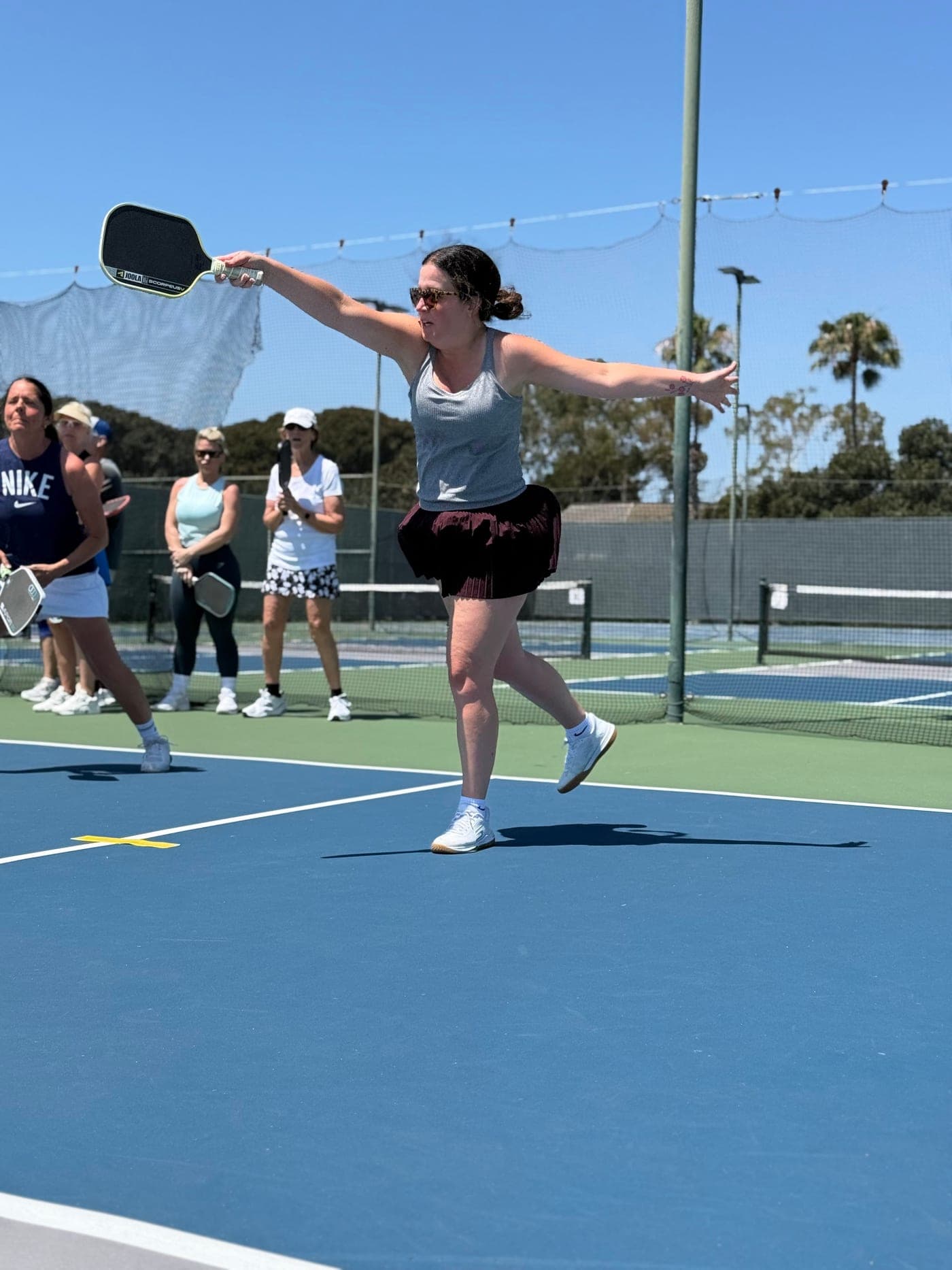 Jenny H. reaching wide for a backhand while the group watches